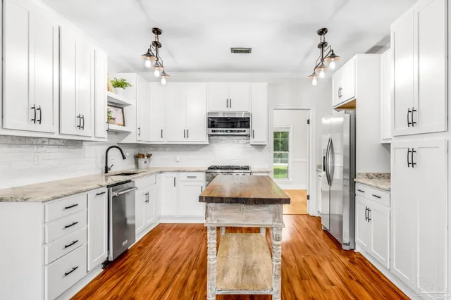 a kitchen with stainless steel appliances granite countertop a stove refrigerator and cabinets