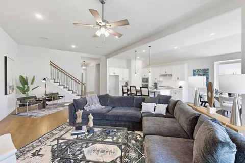 a living room with furniture kitchen view and a chandelier