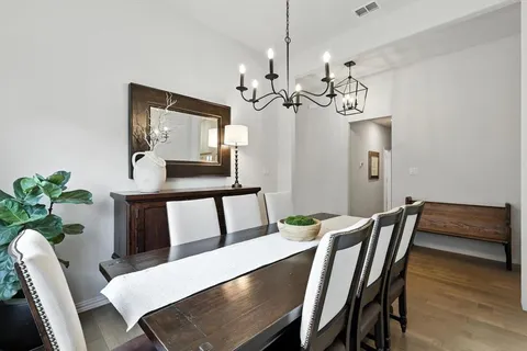 a view of a dining room with furniture a chandelier and wooden floor