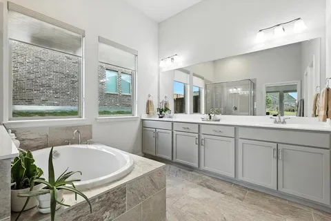 a spacious bathroom with a tub sink and mirror