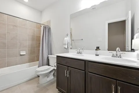 a bathroom with a double vanity sink toilet and shower