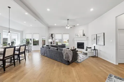 a living room with furniture a fireplace and a dining table with wooden floor