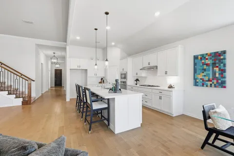 a kitchen with kitchen island a dining table chairs sink and cabinets
