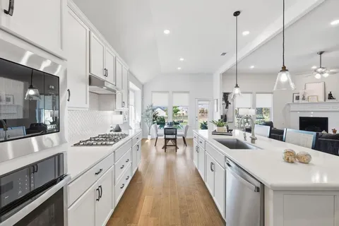 a large kitchen with stainless steel appliances a stove a sink a oven a dining table and chairs