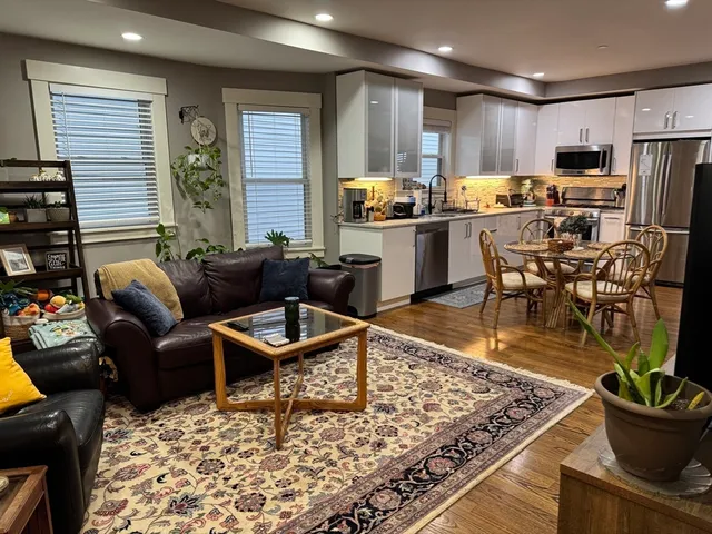 a living room with stainless steel appliances kitchen island granite countertop a refrigerator and a stove top oven