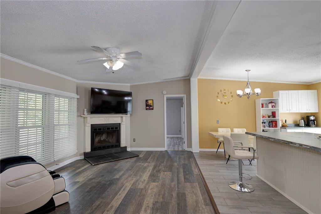 184 Floyd Road Pine Mountain, GA 31822 - Photo 16 of 27 Living space with wood-finish flooring, a fireplace featuring a stone surround, and a ceiling fan with integrated lighting