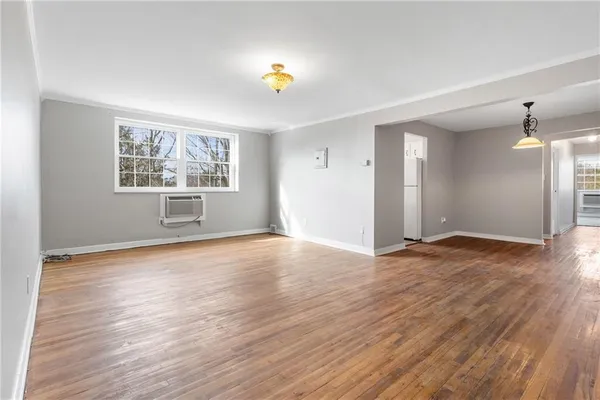an empty room with wooden floor and window