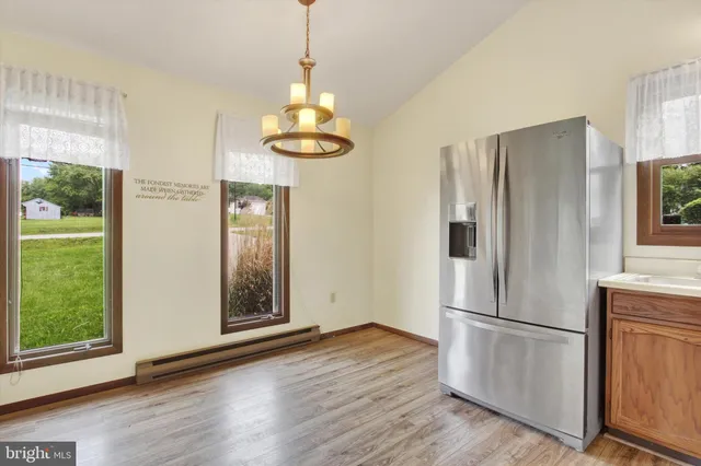 a view of kitchen with stainless steel appliances wooden floor and window
