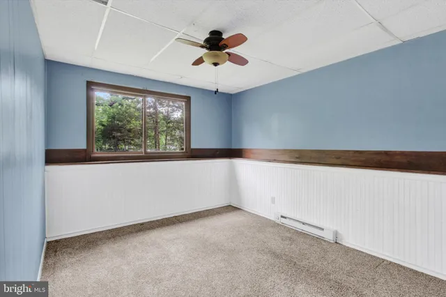 an empty room with a ceiling fan and window