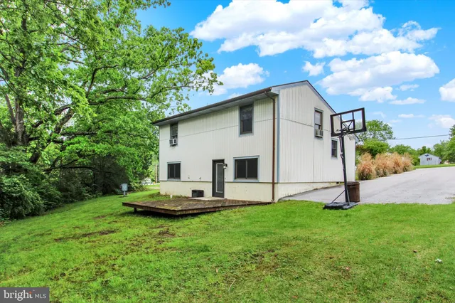 a white house with a small yard and large trees