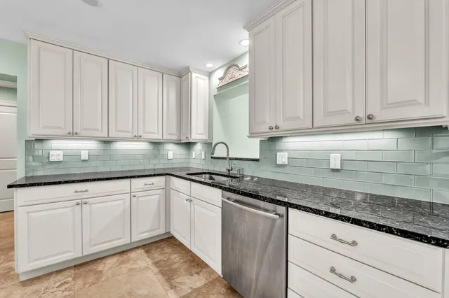 a kitchen with granite countertop white cabinets and sink