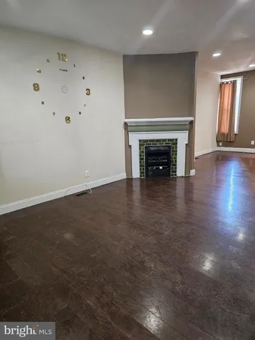an empty room with wooden floor fireplace and windows