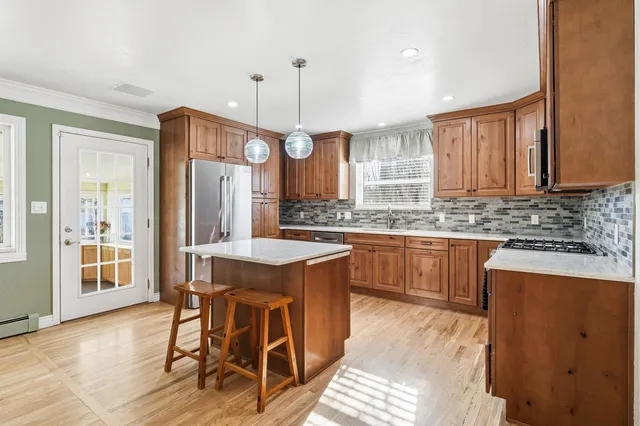 a kitchen with granite countertop a stove a sink a refrigerator and wooden cabinets