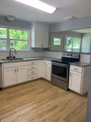 a kitchen with granite countertop a sink cabinets and stainless steel appliances