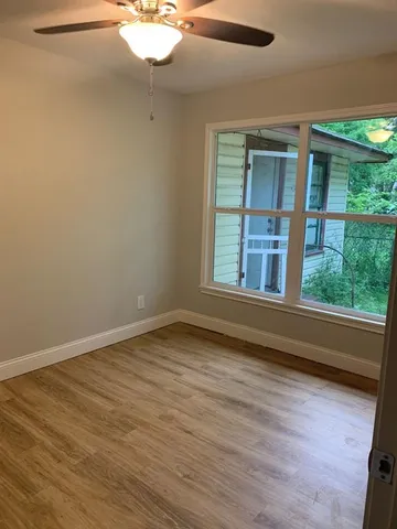 a view of an empty room with wooden floor and a window
