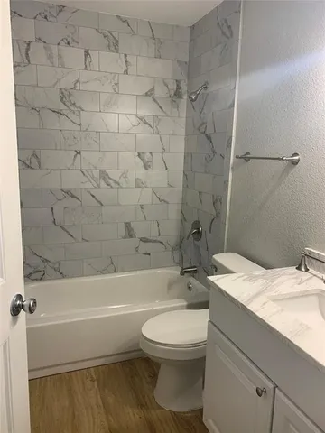 a bathroom with a granite countertop toilet a sink and a bathtub