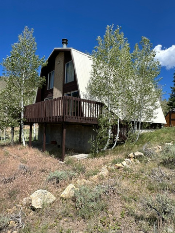 1085 West Elk Road Helper, UT 84526 - Photo 2 of 40 A-frame residence featuring a brown wood-paneled exterior, white metal roof, and an elevated wood deck with railings