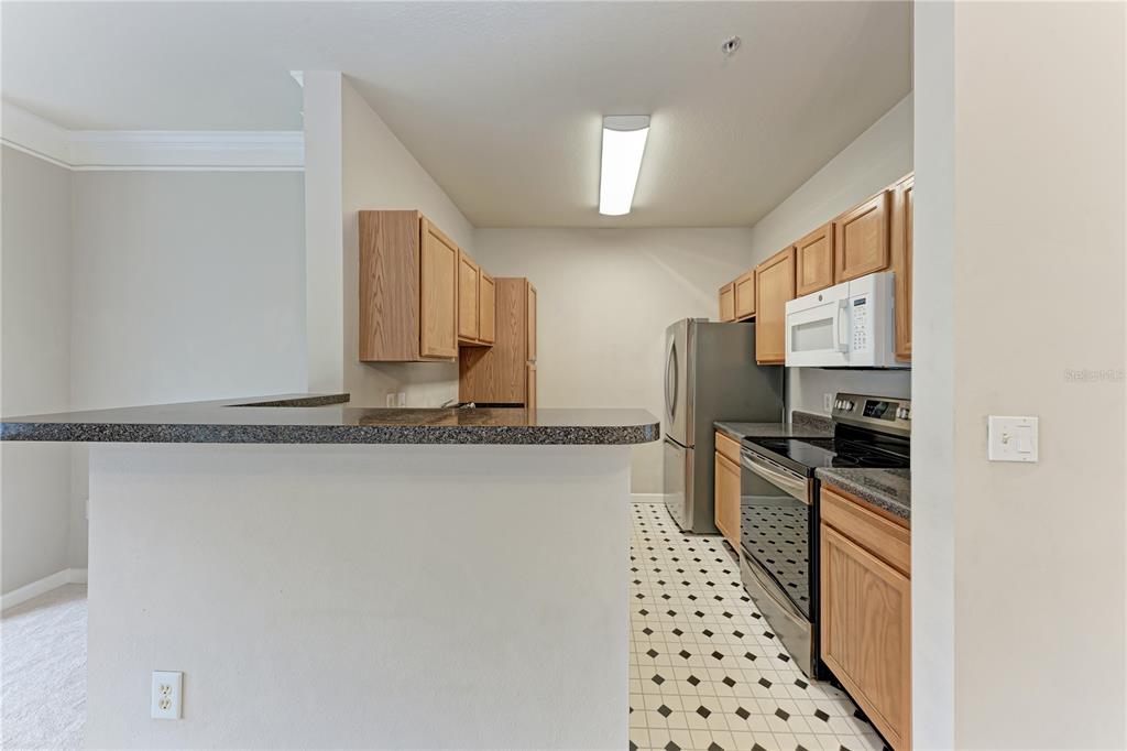 4802 51st Street West, Unit 1122 Bradenton, FL 34210 - Photo 14 of 37 a kitchen with granite countertop a refrigerator stove and sink