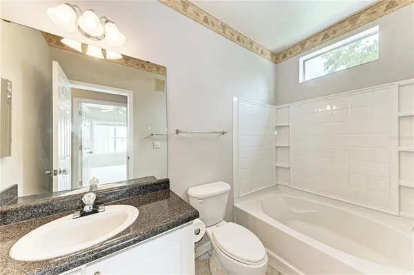 a bathroom with a granite countertop sink toilet mirror and bathtub