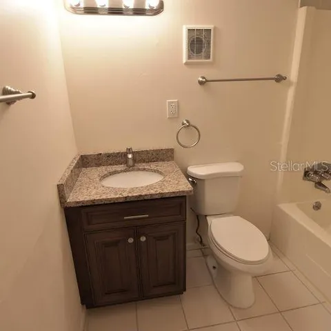 a bathroom with a granite countertop toilet and a sink