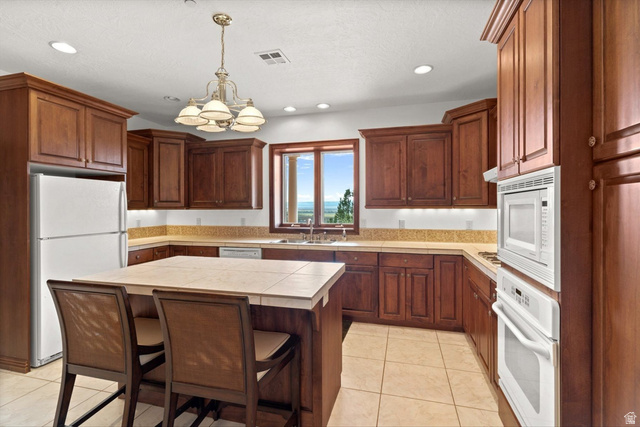 5615 East Eight Mile Gap Road Kanab, UT 84741 - Photo 53 of 81 Kitchen featuring white appliances, a breakfast bar, tile counters, hanging lights, and light tile patterned floors