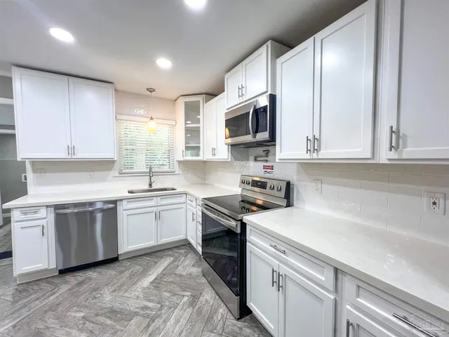 a kitchen with white cabinets appliances and a sink