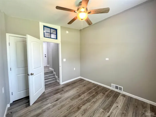 a view of empty room with wooden floor and ceiling fan