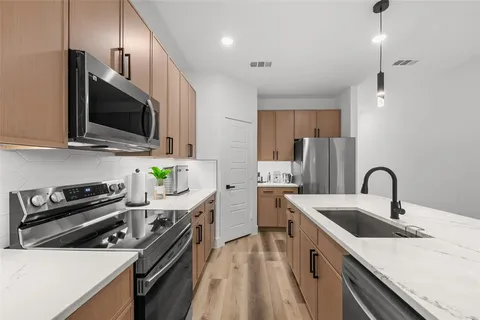 a kitchen with stainless steel appliances kitchen island granite countertop a table chairs sink and cabinets