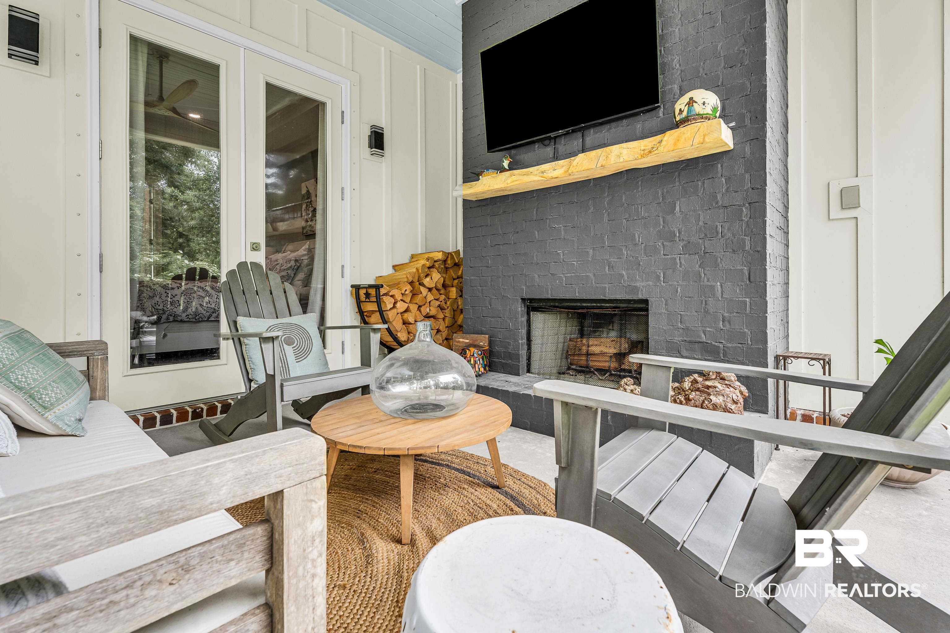 17541 Polo Ridge Boulevard Fairhope, AL 36532 - Photo 13 of 19 Outdoor living space featuring a brick fireplace with a wood mantle, concrete flooring, and white board-and-batten siding