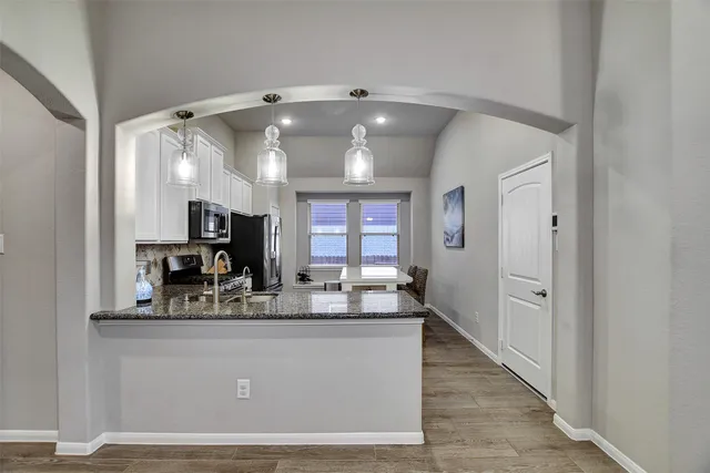 a room with kitchen island a chandelier stainless steel appliances a sink and a refrigerator