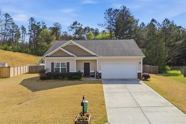 a front view of house with yard and trees in the background