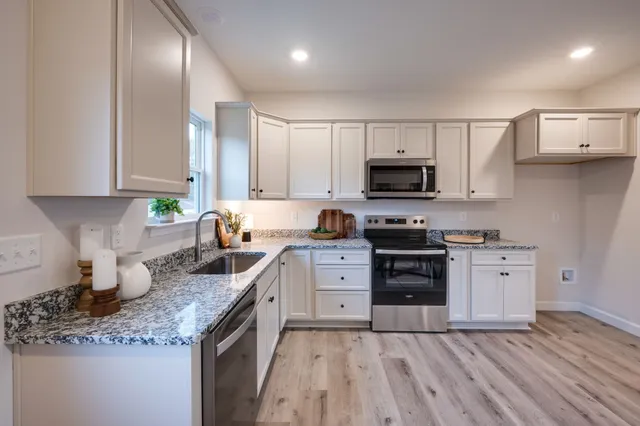 a kitchen with stainless steel appliances granite countertop a stove a sink and a microwave