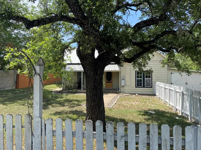 a view of a wooden house with a large tree