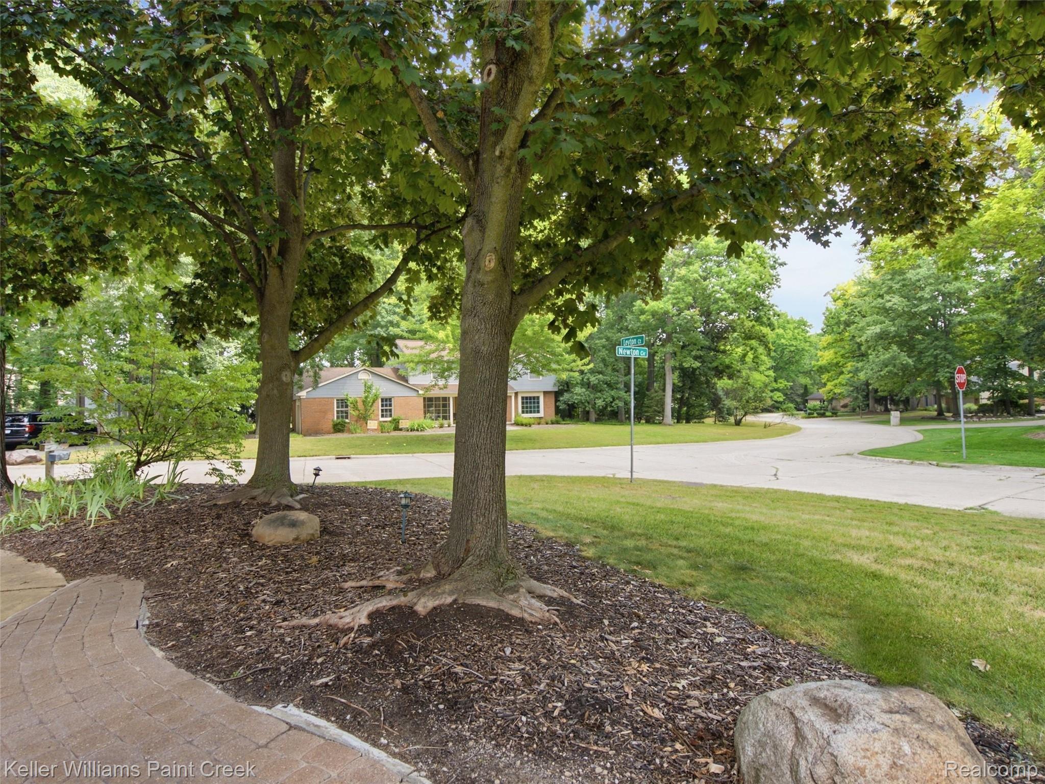 2950 Leyton Court Rochester, MI 48306 - Photo 46 of 46 Mature trees with mulched beds, a paved walkway, and manicured lawn