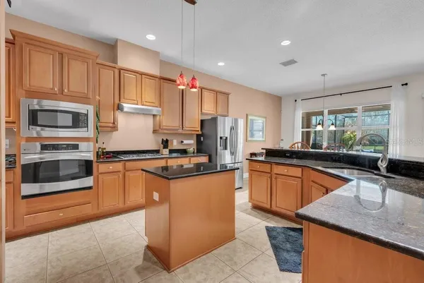 a kitchen with granite countertop a sink counter top space and stainless steel appliances