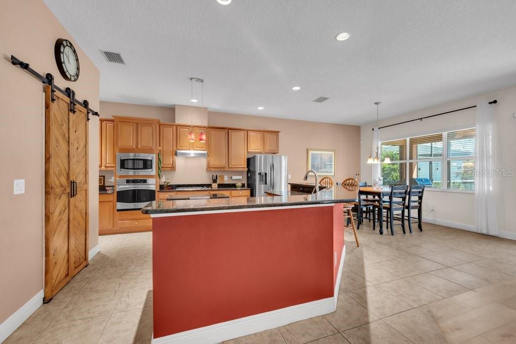 5920 Fishhawk Crossing Boulevard Lithia, FL 33547 - Photo 10 of 61 a large kitchen with kitchen island a large counter top dining table and stainless steel appliances