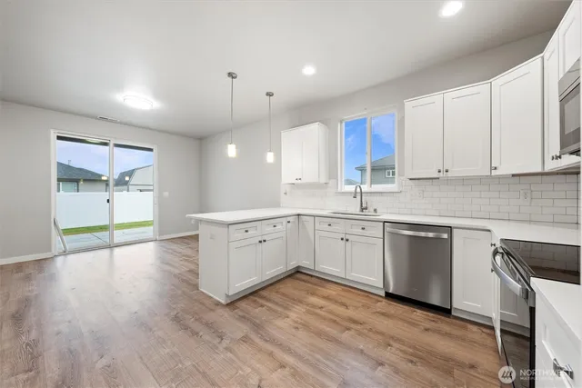 a large white kitchen with wooden floors white cabinets and stainless steel appliances