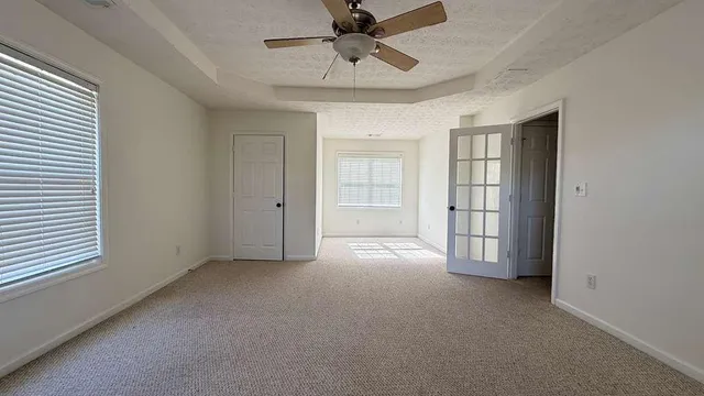 en empty room with windows and ceiling fan