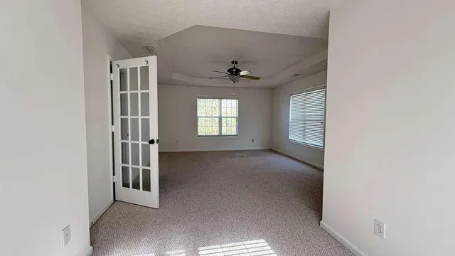 an empty room with windows and ceiling fan