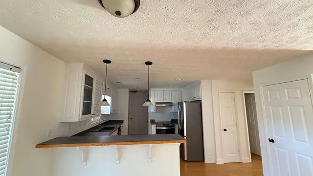 a view of a kitchen with stainless steel appliances granite countertop a refrigerator and a stove
