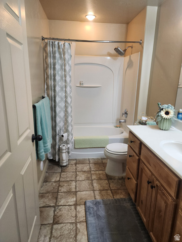 2525 West 450 South, Unit 8 Springville, UT 84663 - Photo 15 of 22 Bathroom featuring a tub/shower combination with a single-handle faucet, a wood-finish vanity with a white countertop and integrated sink, a toilet, and textured floor tiling