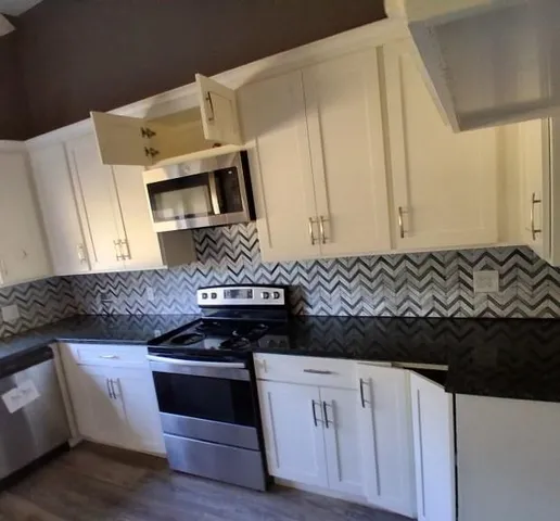 a kitchen with stainless steel appliances granite countertop a stove and a microwave