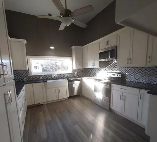 a kitchen with stainless steel appliances kitchen island granite countertop a stove a sink and white cabinets