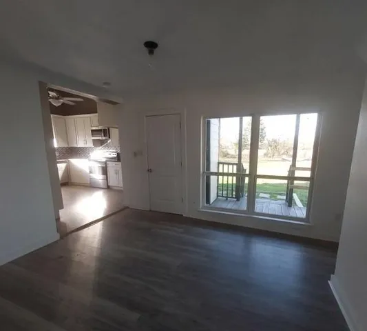 an empty room with wooden floor and windows