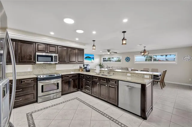 an open kitchen with kitchen island granite countertop wooden cabinets and stainless steel appliances
