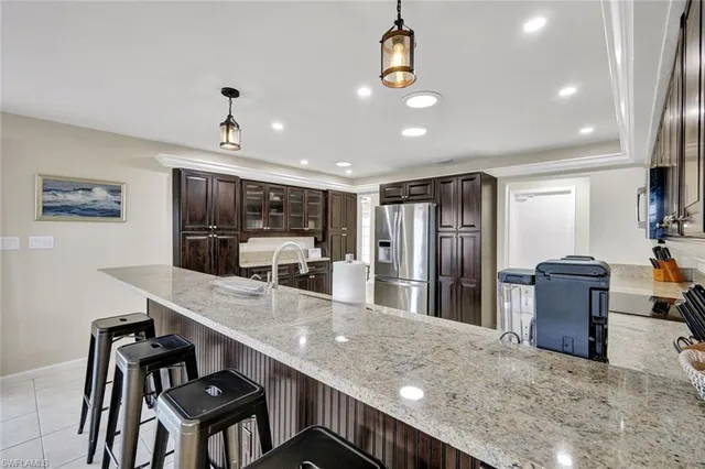 a kitchen with stainless steel appliances kitchen island granite countertop a table chairs in it and wooden floors