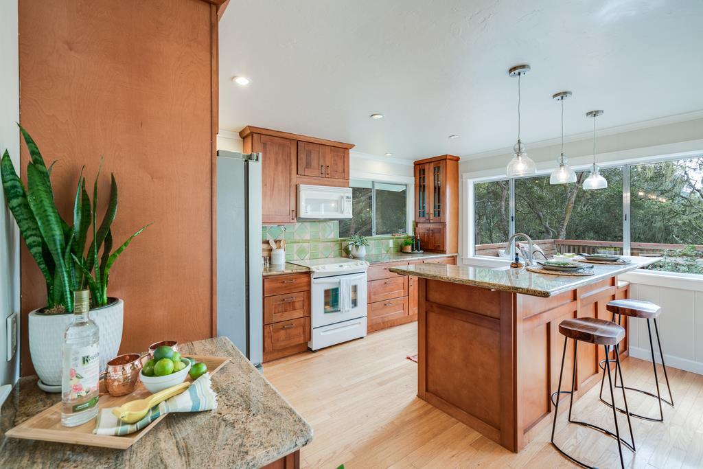 94 Robak Drive La Selva Beach, CA 95076 - Photo 4 of 24 a kitchen with stainless steel appliances kitchen island granite countertop a refrigerator a stove a sink a dining table and chairs with wooden floor