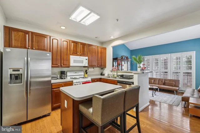 a kitchen with stainless steel appliances a stove a refrigerator a sink a dining table and chairs