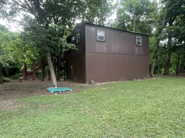 a backyard of a house with lots of plants and large tree