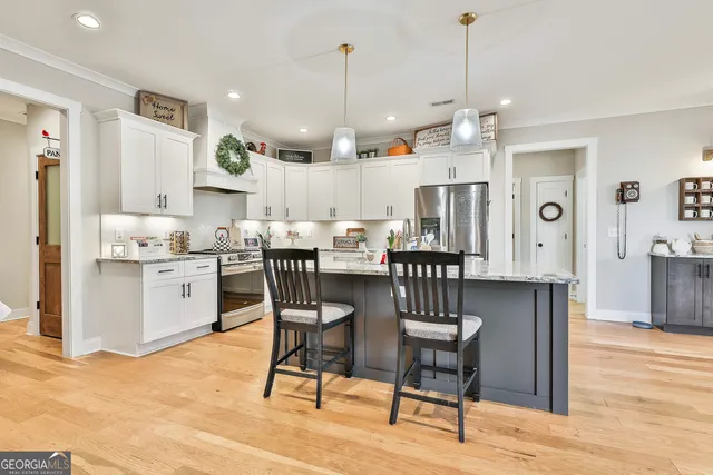 a open kitchen with stainless steel appliances granite countertop a dining table chairs refrigerator and cabinets